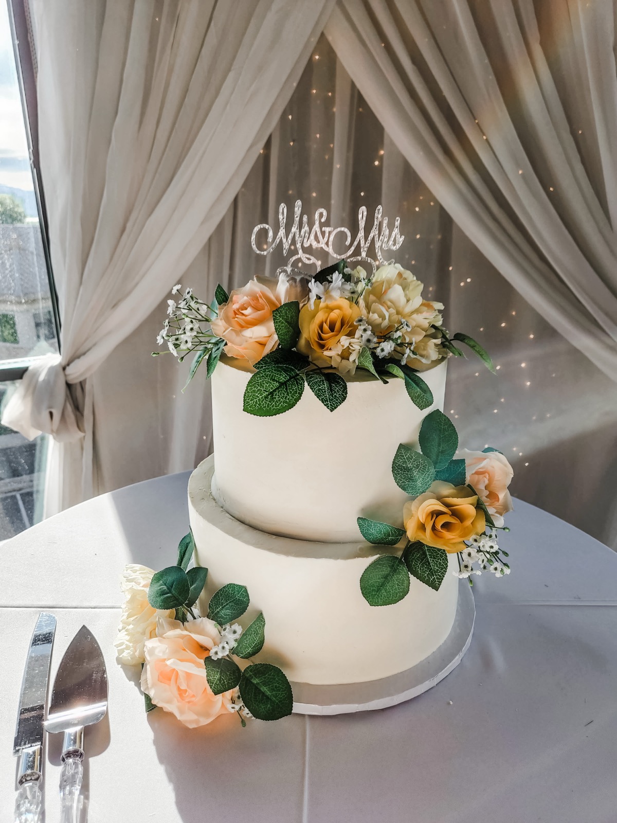 Two-tier wedding cake with peach flowers and a Mr and Mrs topper
