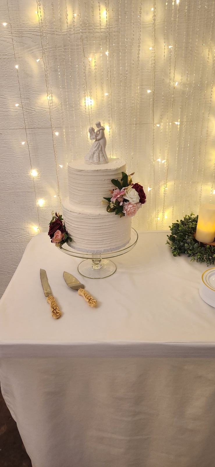 Wedding cake with topper against warm string lights